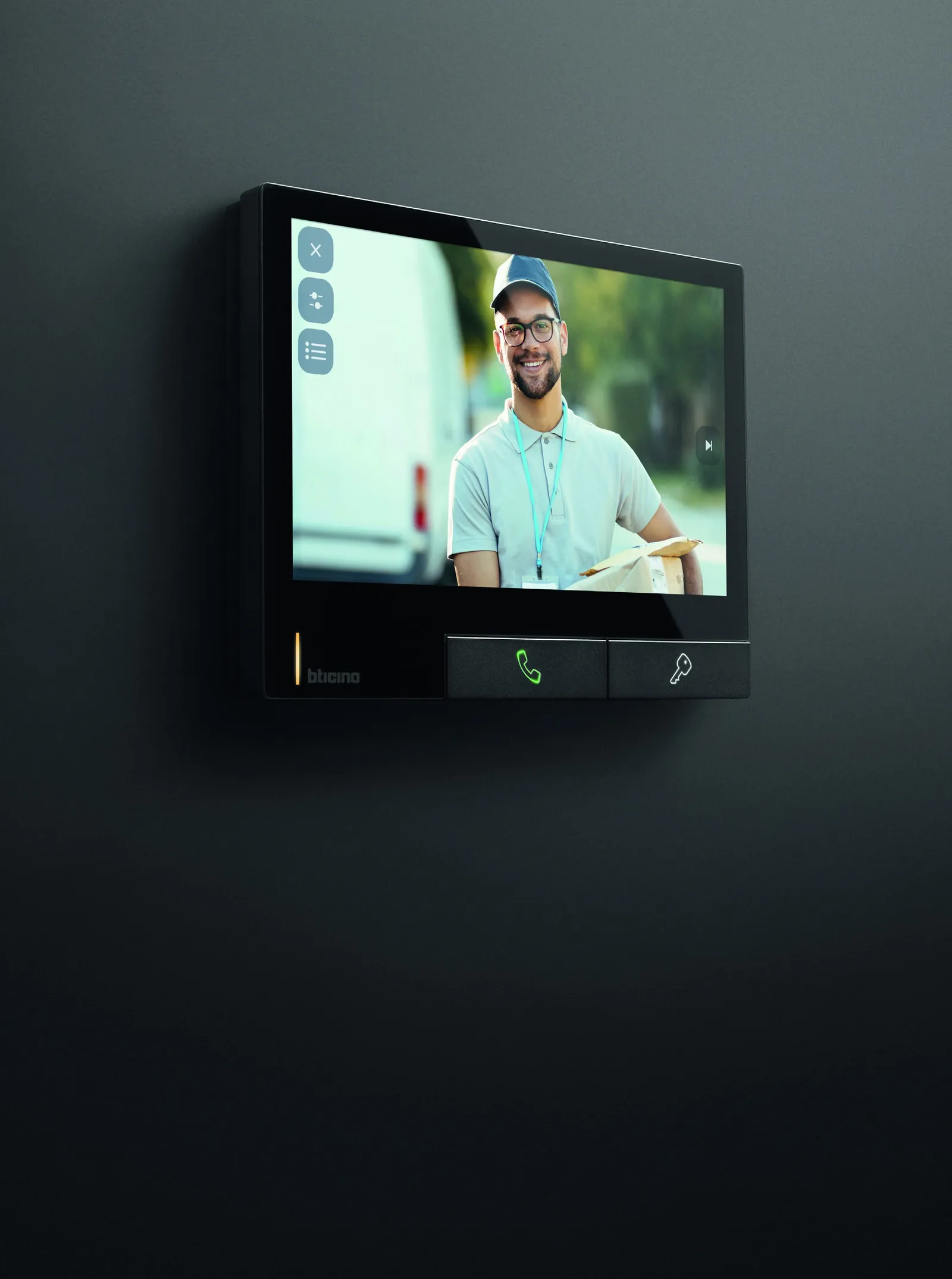 Moniteur vidéo BTicino Classe 300X noir sur un mur anthracite, un livreur à l’écran
