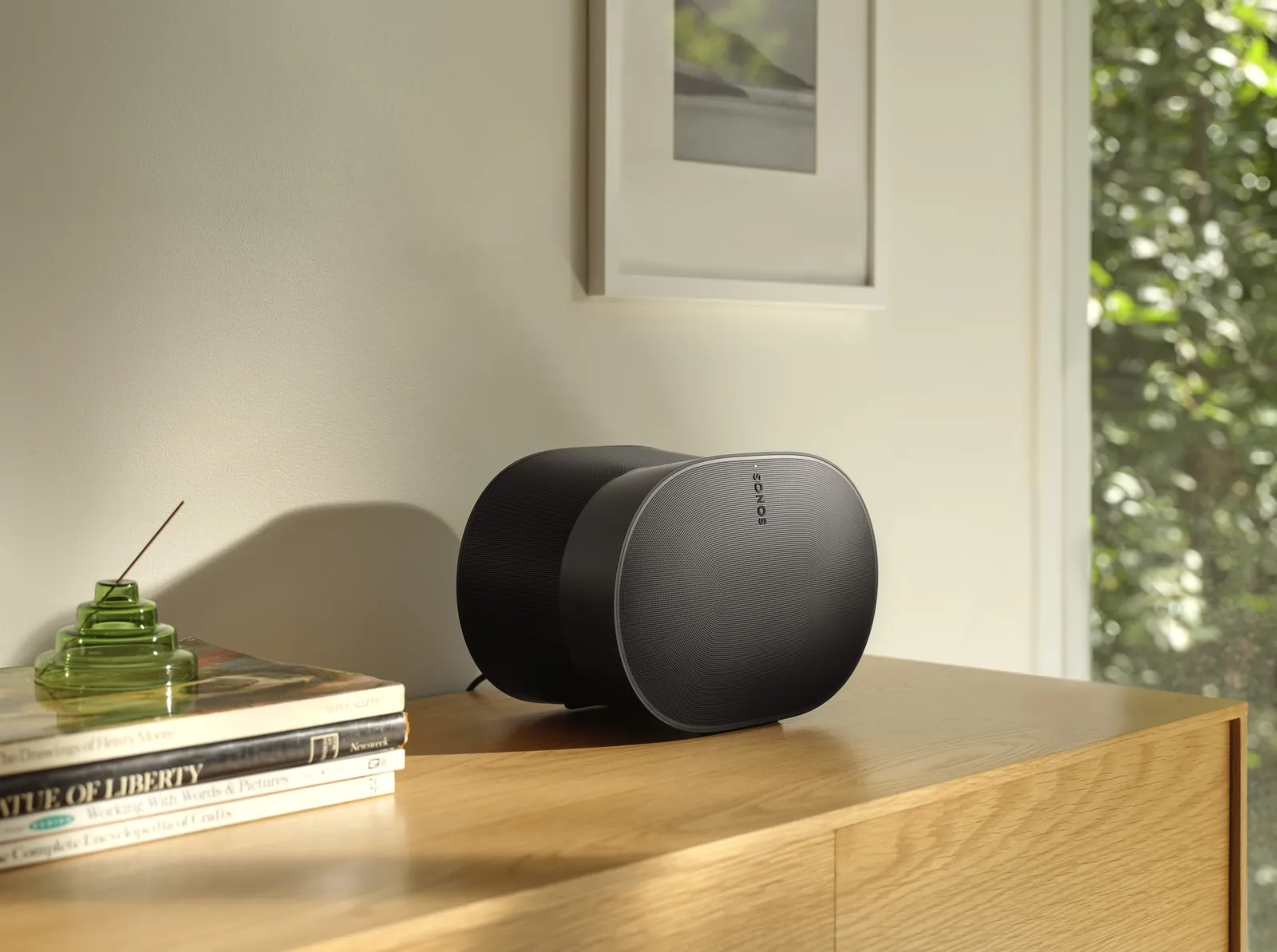 Enceinte Sonos Era 300 noire sur un buffet en chêne, en lumière naturelle