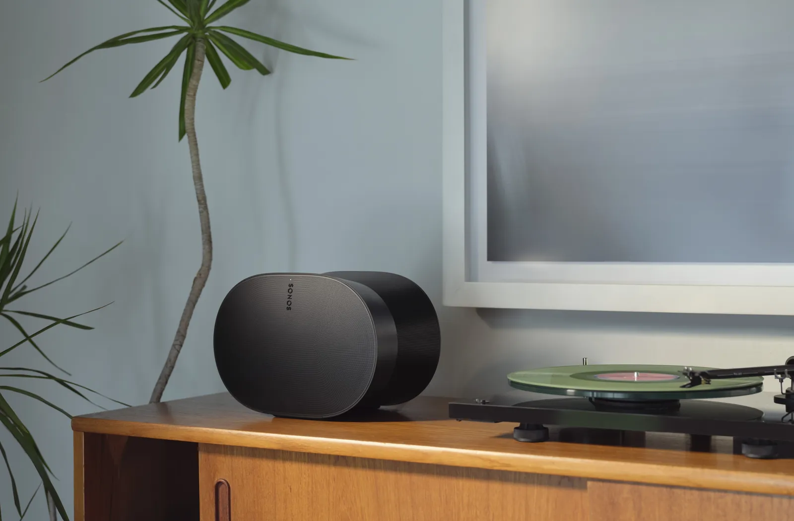 Enceinte Sonos Era 300 noire à côté d’une platine vinyle dans un salon